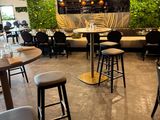 tables and stools in a restaurant with plants growing on the walls