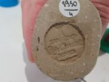 a hand holding a piece of stone with a stamp on it