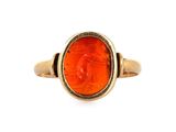 a close up of a gold ring with an orange stone in the center