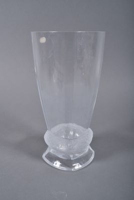 a clear glass vase with a circular base on a gray surface