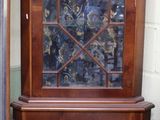 une armoire en bois avec une porte vitrée, dans un coin de la pièce