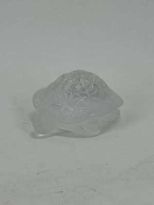 a glass turtle that is sitting on a white surface