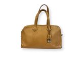 Le sac à main en cuir beige est posé sur une surface blanche.