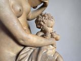 marble statue of a woman holding a child and a drum