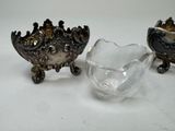 two silver and glass bowls sitting next to each other on a white surface