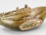 a gold boat shaped object on a white surface