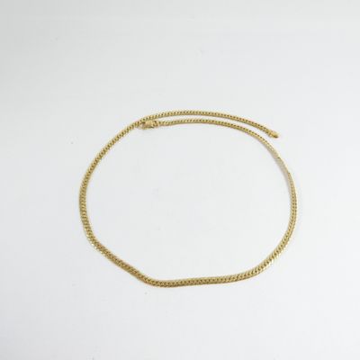 gros plan d'un bracelet en chaîne en or sur une surface blanche