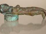 statue of a person laying on a table with a reflection on the surface