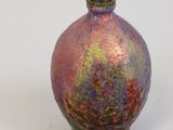 un petit vase posé sur une surface blanche