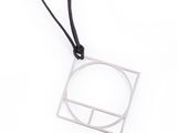 un collier composé d'un carré en argent et d'un cordon noir sur fond blanc