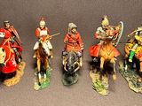 seven figurines of men riding on horses and horses