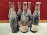 Quatre bouteilles de vin sont posées sur une table devant un mur rouge.