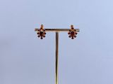 paire de boucles d'oreilles en or et grenat, posée sur un socle en marbre