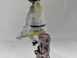 porcelain figurine of a boy on a tree stump with a baseball bat