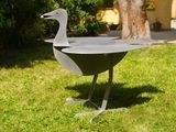 a metal bird that is standing in the grass