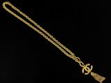 a gold necklace with a tassel on a black background