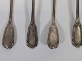 four spoons are lined up in a row on a white surface