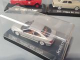 three model cars in a clear display case on a table