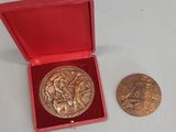 une image représentant une médaille d'or dans un coffret rouge, à côté d'une pièce d'or