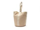 un sac fourre-tout beige et blanc posé sur une surface blanche