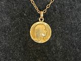 a gold coin necklace with a woman ' s face on it
