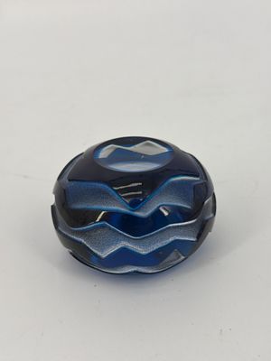 a close up of a blue and black glass bead on a white surface