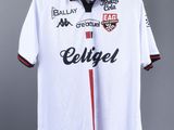 the soccer shirt is hanging on a hanger on a wall
