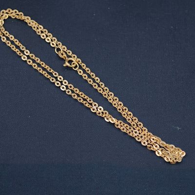 un gros plan d'un collier à chaîne dorée sur fond bleu