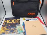 un sac noir posé sur une table, à côté de quelques livres
