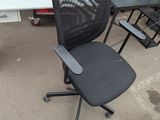 a black office chair sitting in front of a white desk