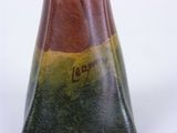 a brown and green vase sitting on a white surface