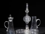 three clear glass vases and a candle holder sitting on a table