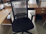 a black office chair sitting in front of a computer desk