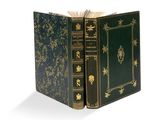 un vieux livre à la couverture verte posé sur une surface blanche