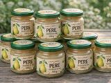six jars of pear jam sit on a table in front of a bush