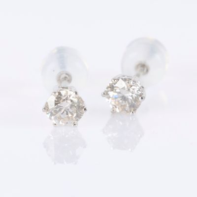 une paire de boucles d'oreilles en diamant posées sur une surface blanche