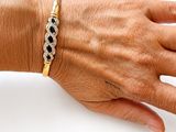 a woman ' s hand with a gold bracelet on it