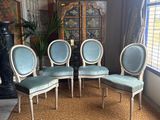 four chairs in a room with a rug and a lamp