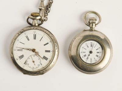 deux montres de poche en argent posées l'une à côté de l'autre sur une surface blanche