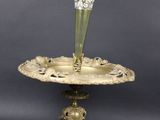 une plaque en laiton ancien sur laquelle est posé un vase en verre vert