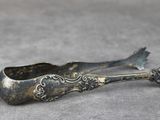 cuillère ancienne en métal argenté, ornée d'un motif floral sur un fond gris