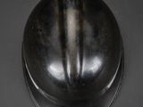 an old black helmet on a black surface with a black background