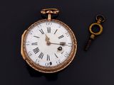 an old pocket watch and a key on a black surface
