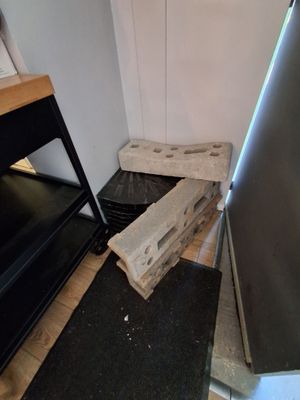 un tas de bois posé par terre à côté d'un réfrigérateur