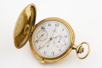 une montre de poche en or posée sur une surface blanche