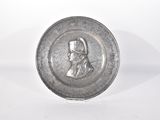 une vieille assiette en argent sur laquelle figure le portrait d'un homme