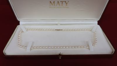 a white box with pearls in it on a red surface