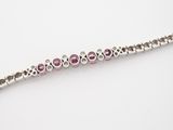 a close up of a silver bracelet with pink stones on it