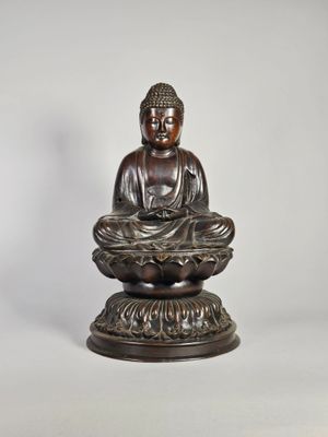 une statue en bronze représentant un Bouddha assis sur une fleur de lotus