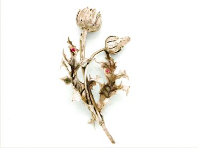 une broche en forme de fleur en argent ornée d'une perle rouge